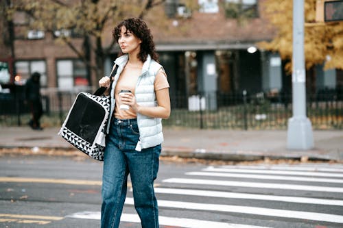 Wanita Dengan Kemeja Putih Dan Jeans Denim Biru Memegang Tas Tangan Hitam Putih