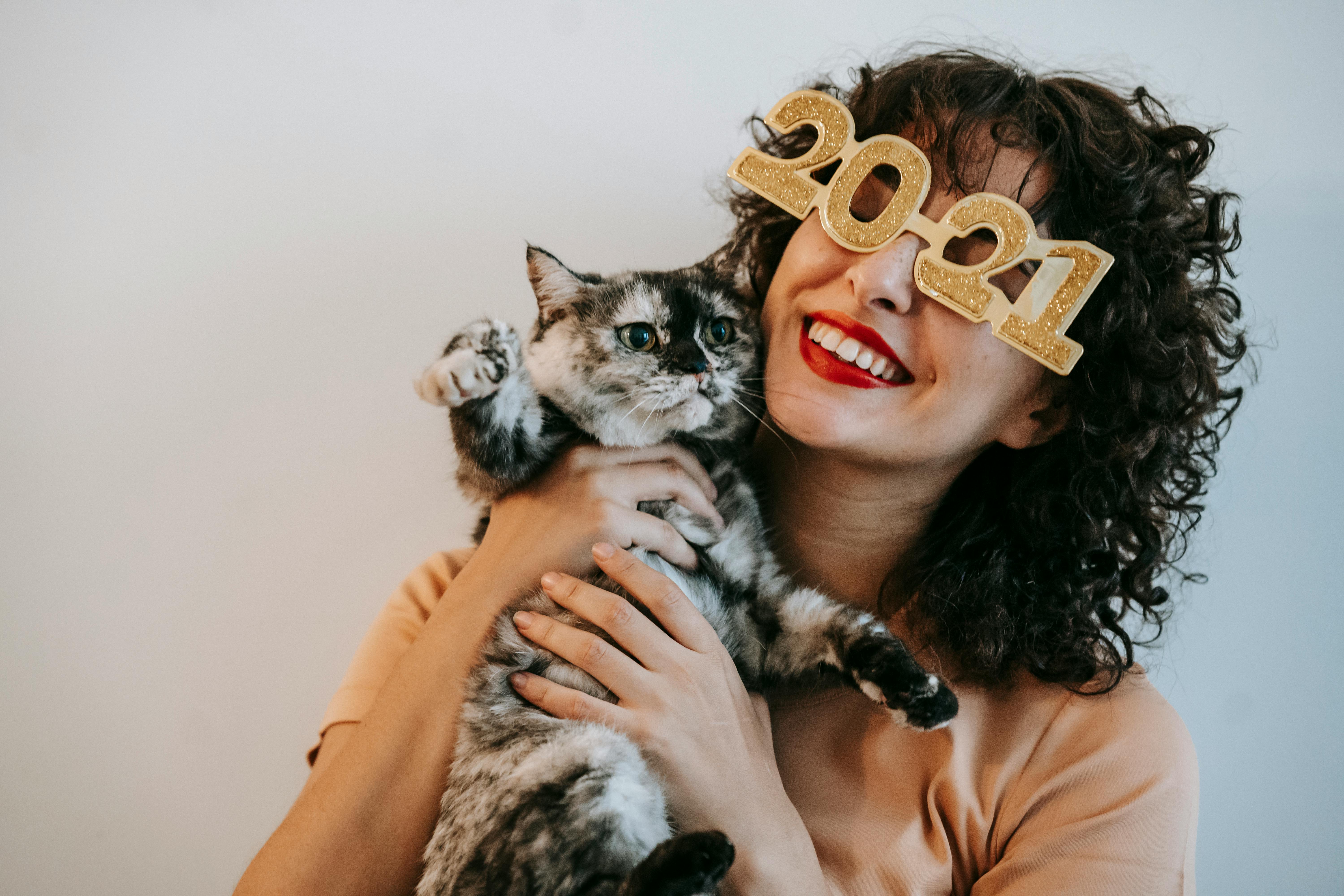 cheerful woman in decorative glasses embracing cute cat