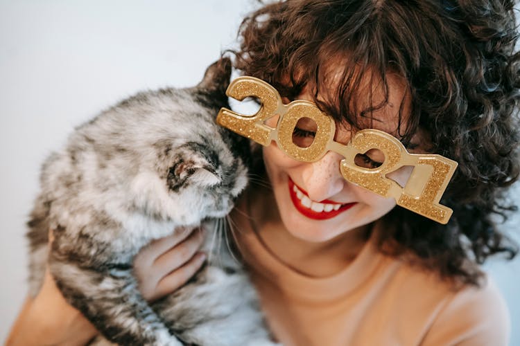 Crop Smiling Woman In New Year Glasses Cuddling Cat