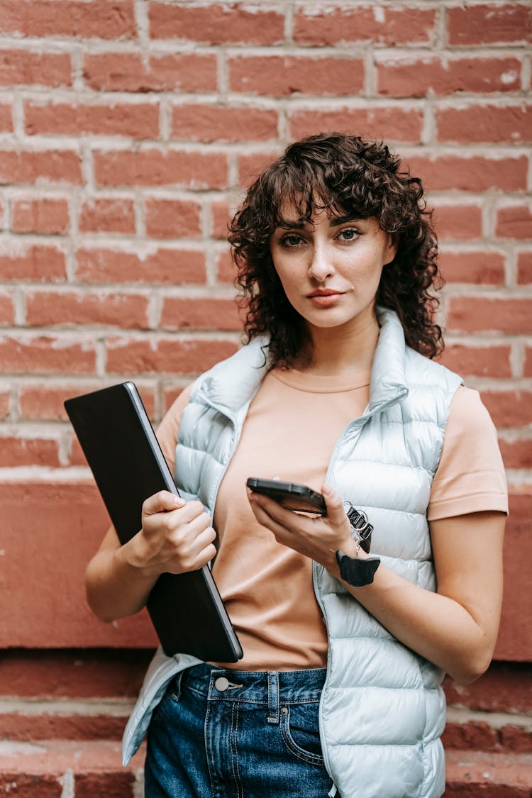 Charming Female Remote Worker With Laptop And Smartphone On Street