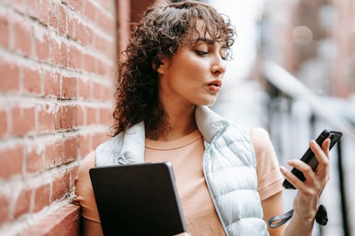 Free Attentive freelancer with laptop watching smartphone in city Stock Photo