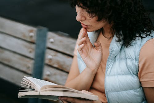 Free Focused young woman reading novel in park Stock Photo
