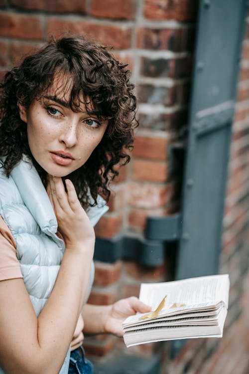 Thoughtful woman with book near building