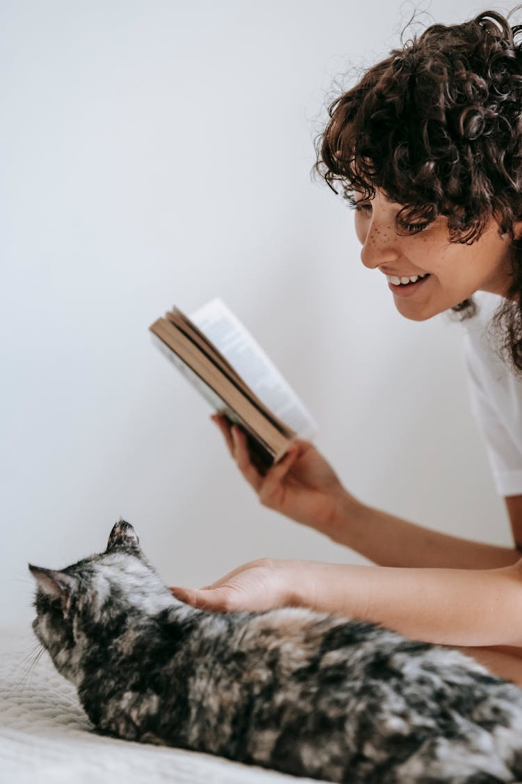 Smiling Woman With Book Stroking Cat