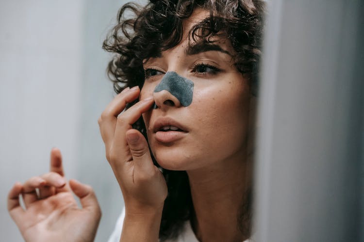 Woman Applying Nose Strip In Bathroom