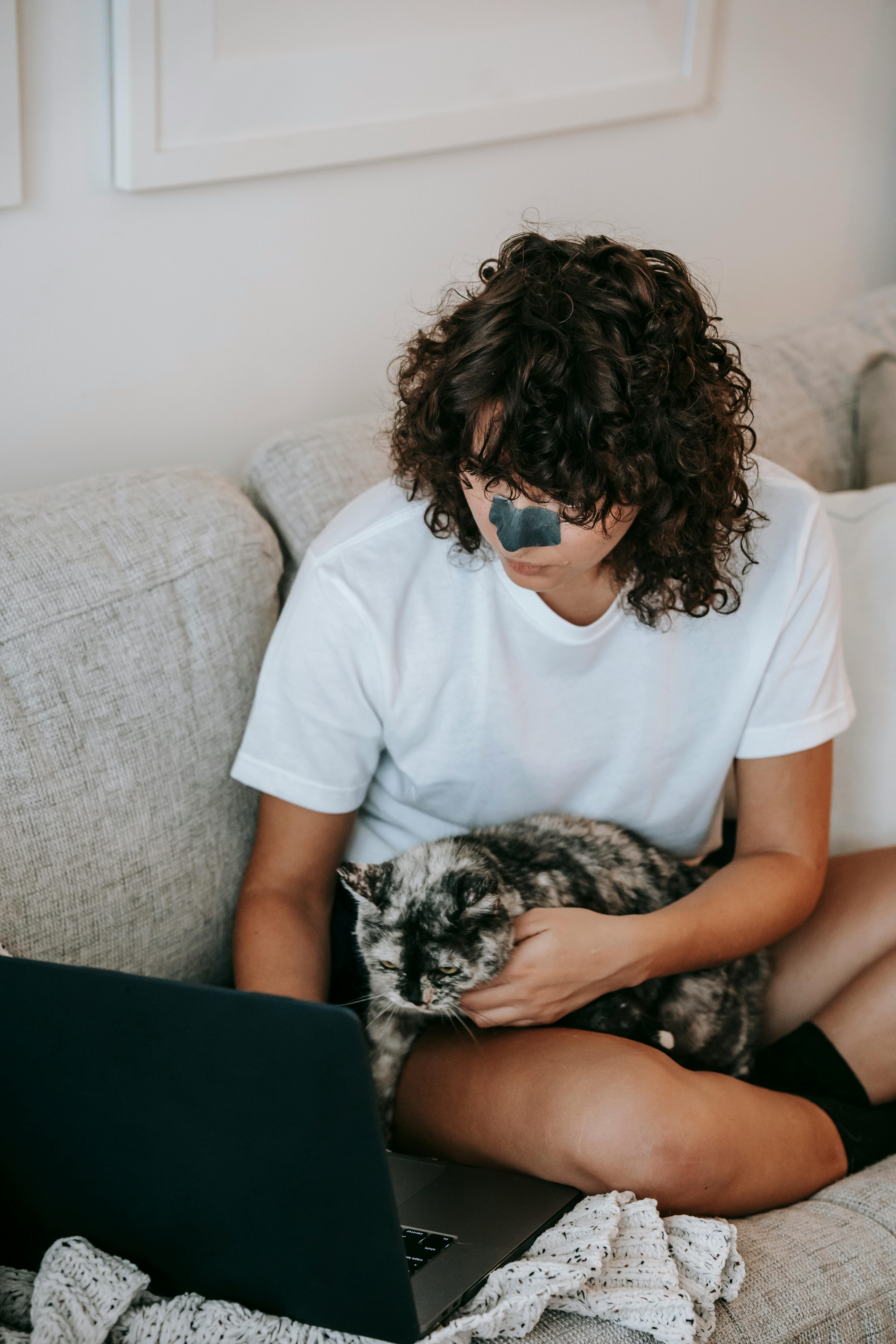 young woman with laptop caressing cat