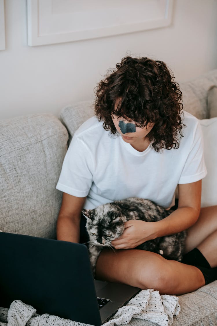 Young Woman With Laptop Caressing Cat