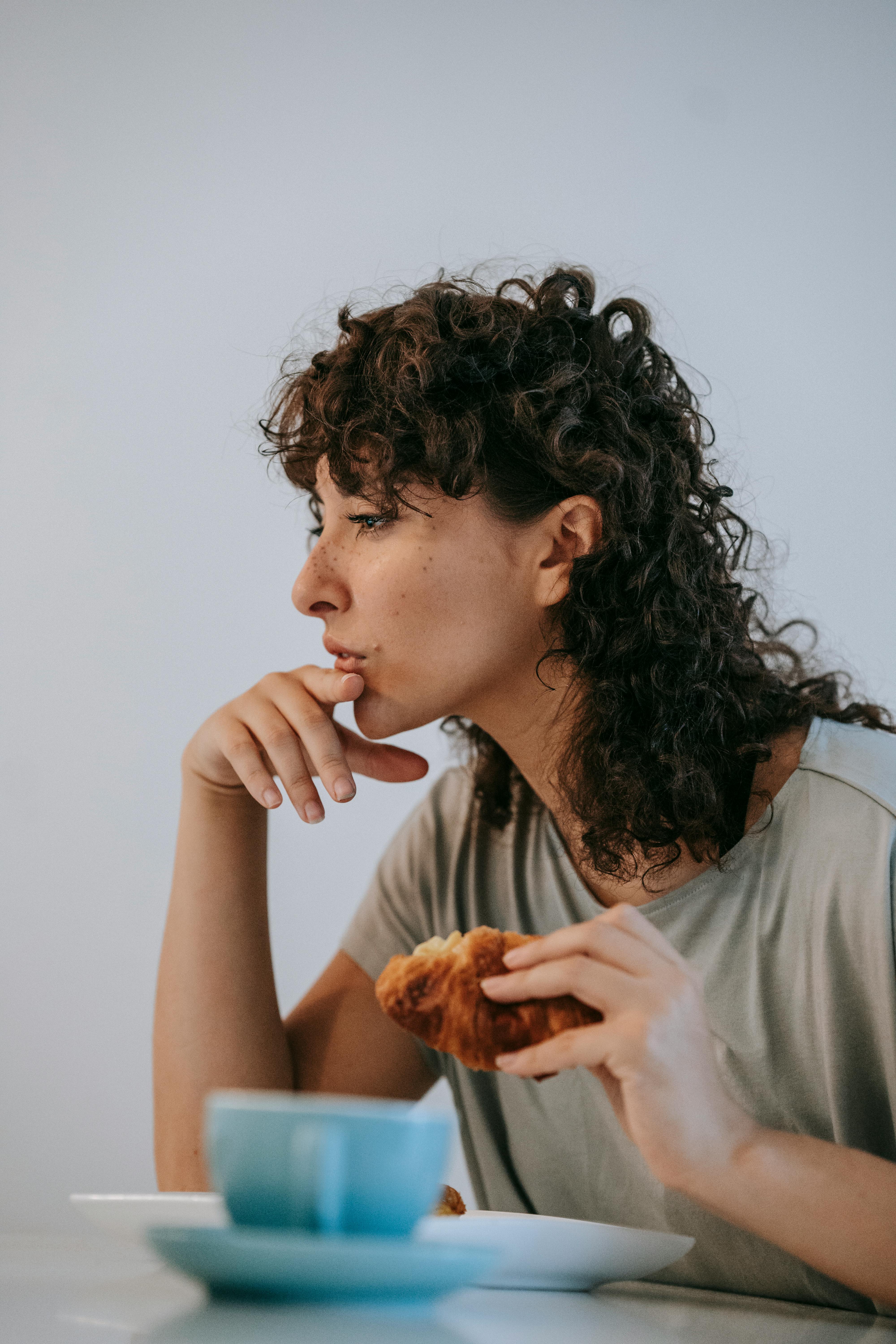 pensive woman with croissant at table