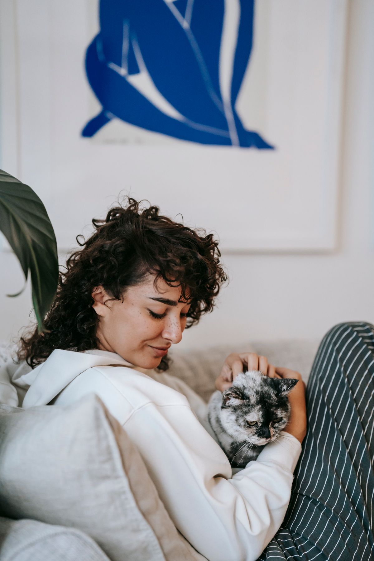 Mulher relaxando no sofá enquanto faz carinho em um gato