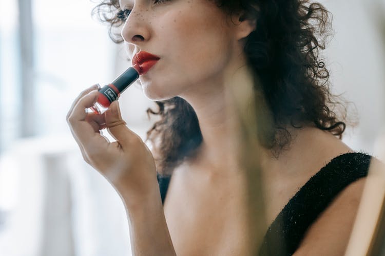 Content Young Woman Applying Red Lipstick On Lips