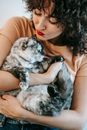 Woman with bright red lips hugging tabby cat