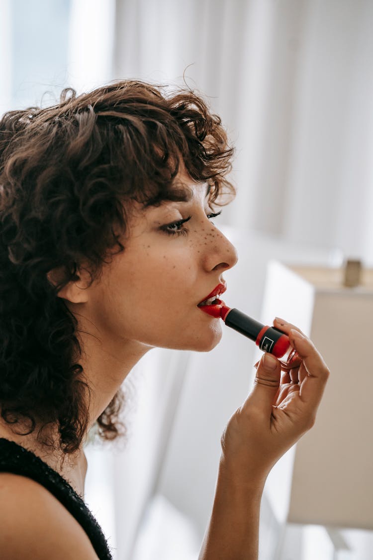 Young Content Woman Applying Red Lipstick