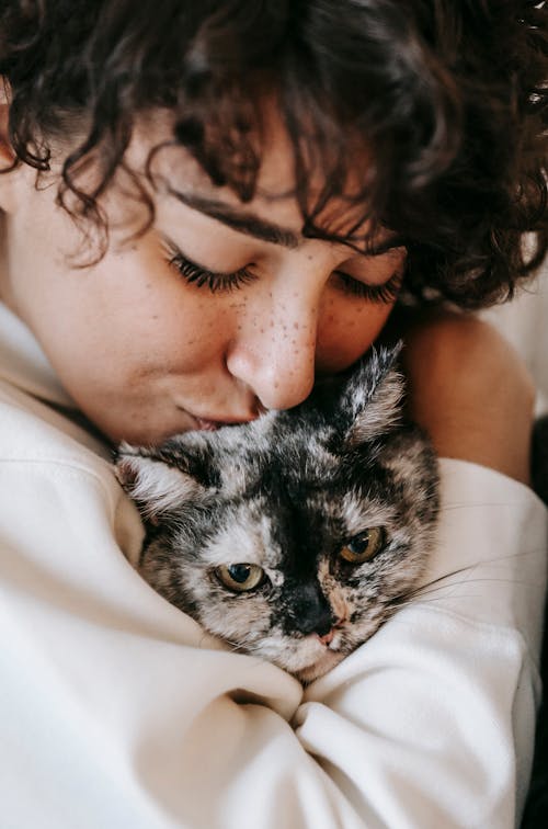 Cheerful female kissing spotted cat