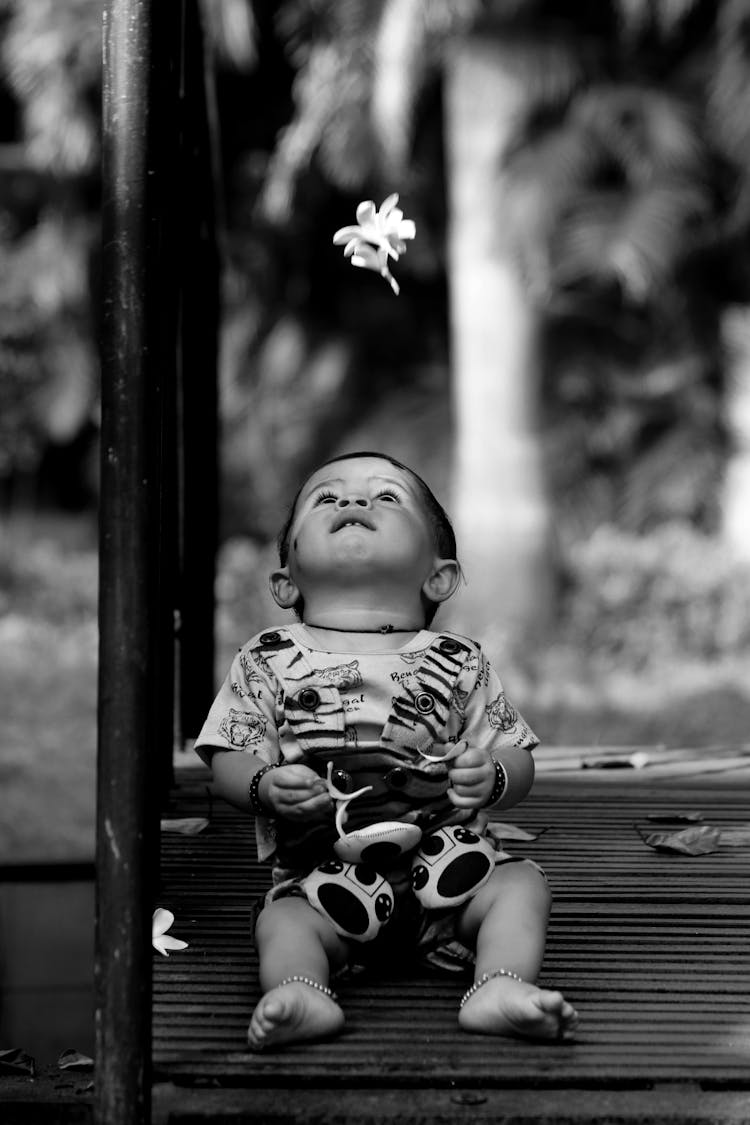 Black And White Photo Of A Boy Looking At A Falling Flower