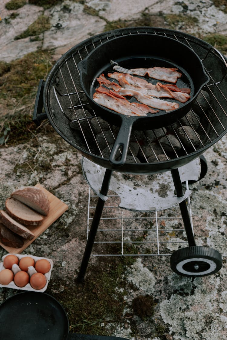 Cooking Pan With Strips Of Meat On Black Charcoal Grill