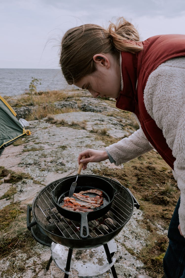 A Woman Cooking On A Pan Placed On A Burning Griller