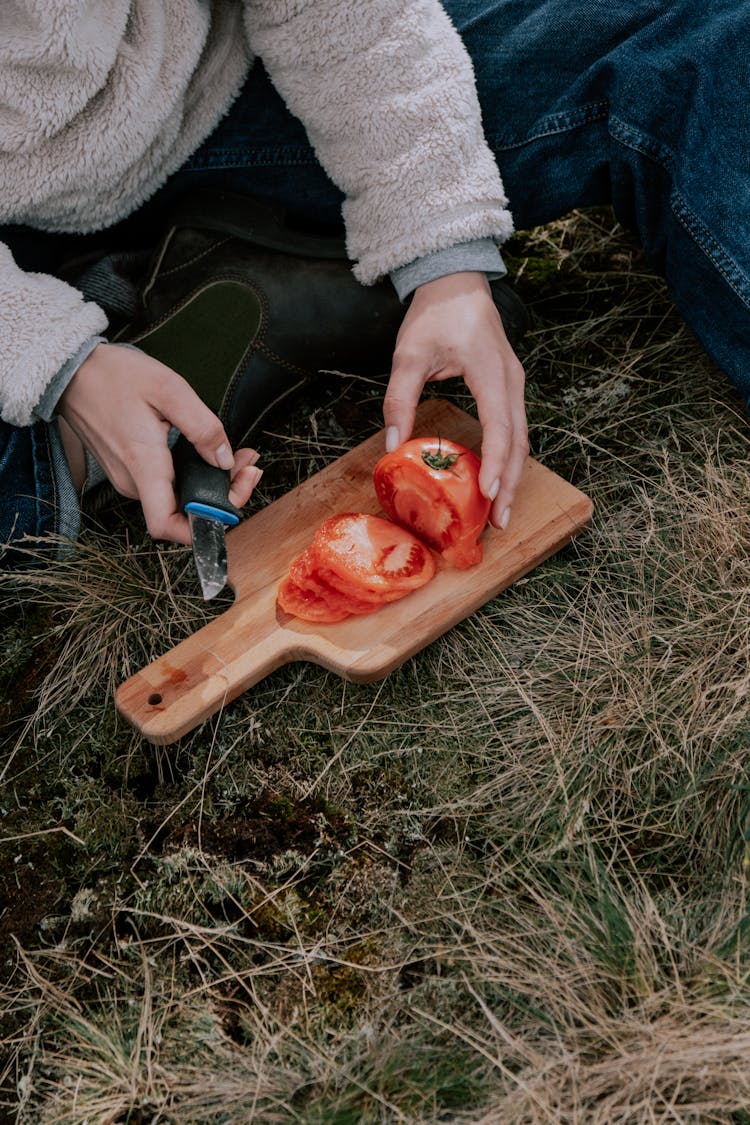 A Person Cutting A Tomato 