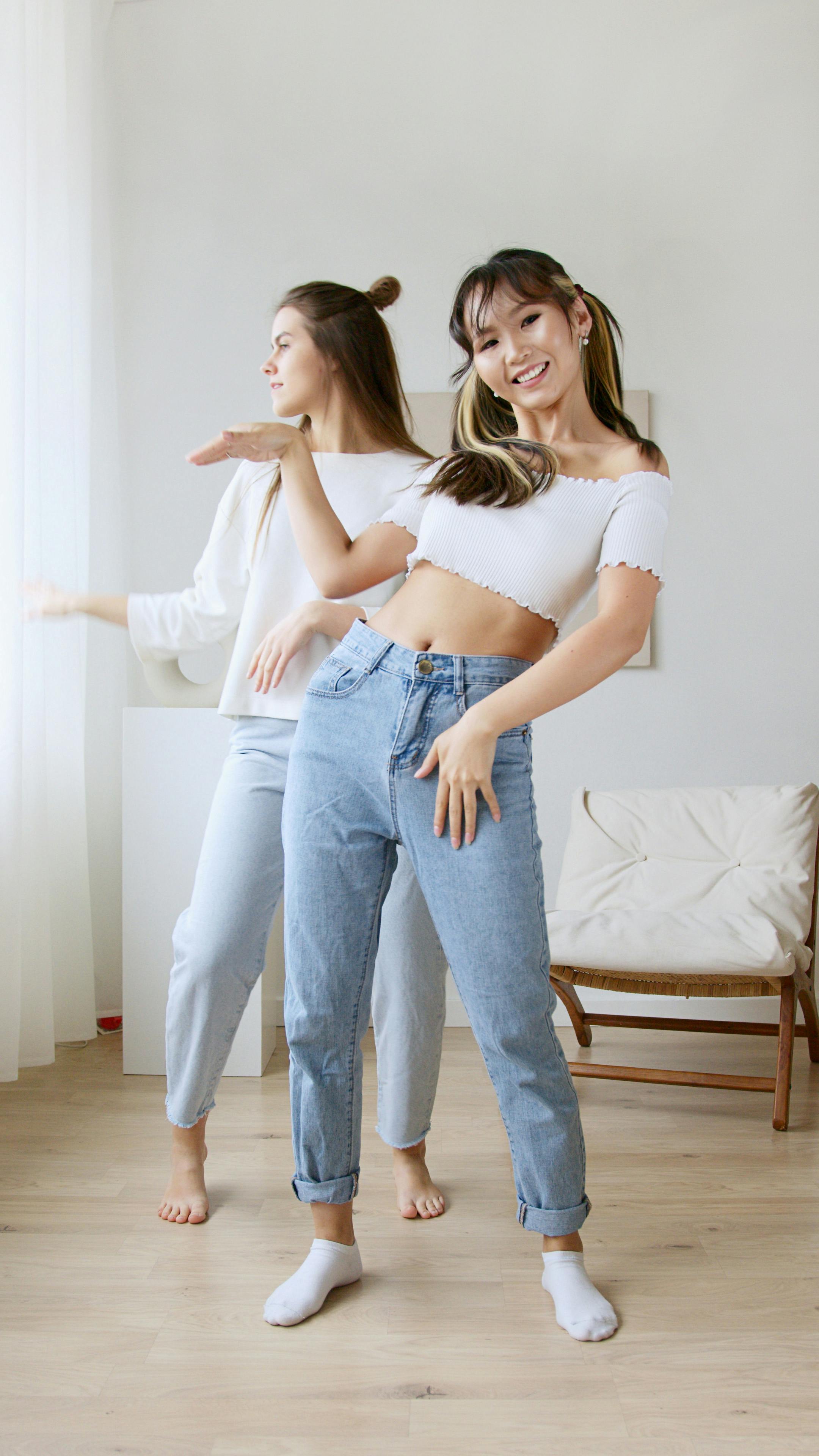 woman in white crop top and blue denim jeans standing beside bed