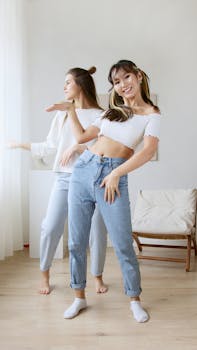 Two young women enjoying a dance session indoors, showcasing happiness and carefree joy.