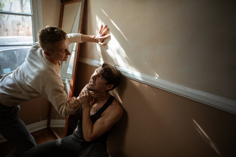 Two Men Fighting Near A Wall Mirror