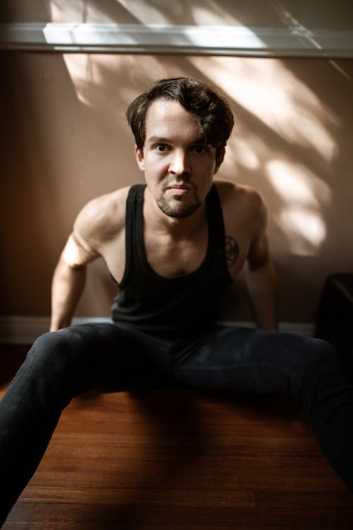 A Man in a Tank Top Sitting on the Floor