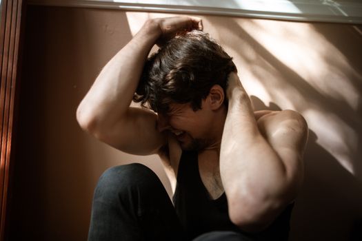 Man in Black Tank Top and Blue Denim Jeans Sitting on White Bed