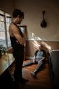Man in Black Tank Top and Pants Looking at a Boy Sitting