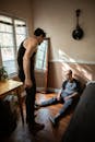 Man in Black Pants Talking to a Boy Sitting on the Floor