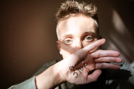 Close-up portrait with hand written 'Please Stop' conveying a message.