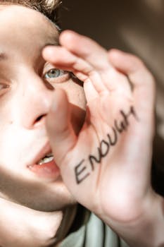 A person holding up their hand with the word 'Enough,' conveying a strong message.