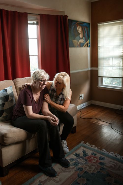 Free Two women sitting on a couch, displaying empathy and support in a cozy living room. Stock Photo