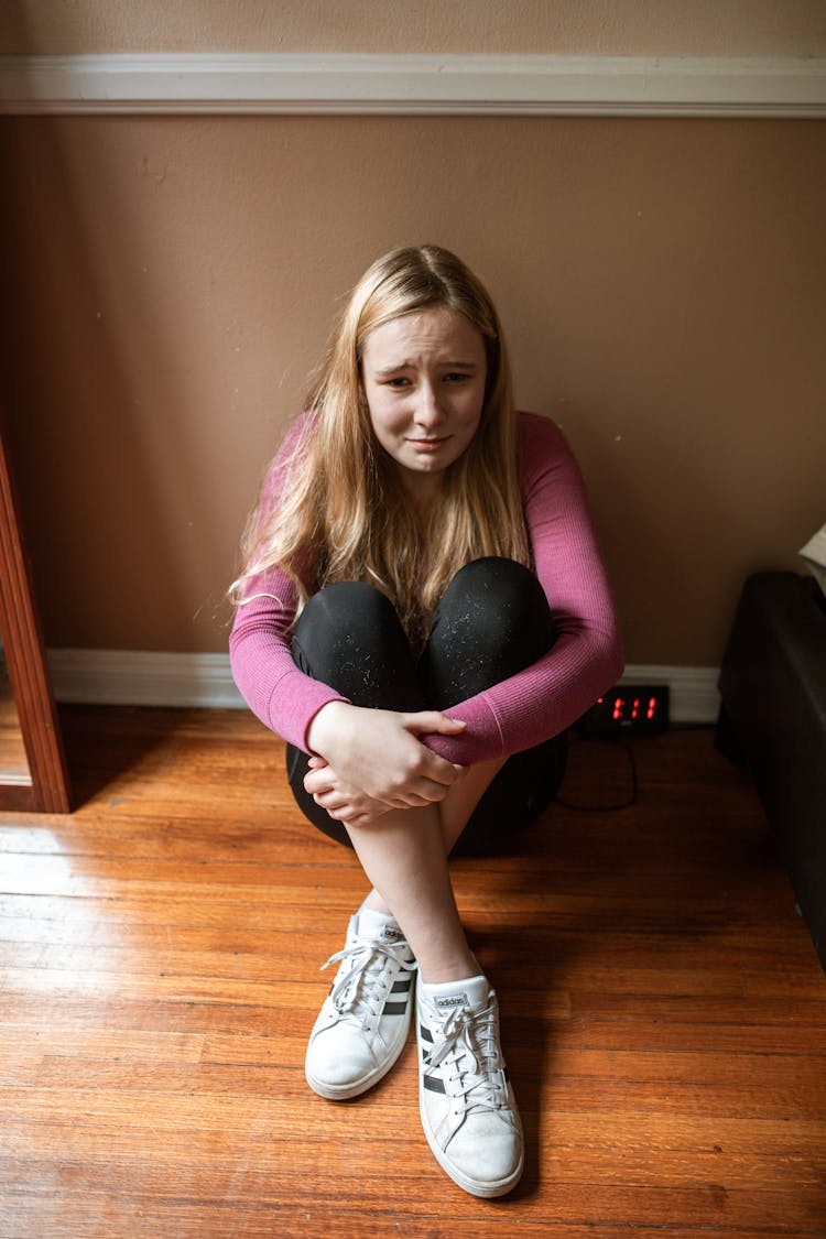 Young Girl In Pink Long Sleeve Shirt Sitting On Floor Crying