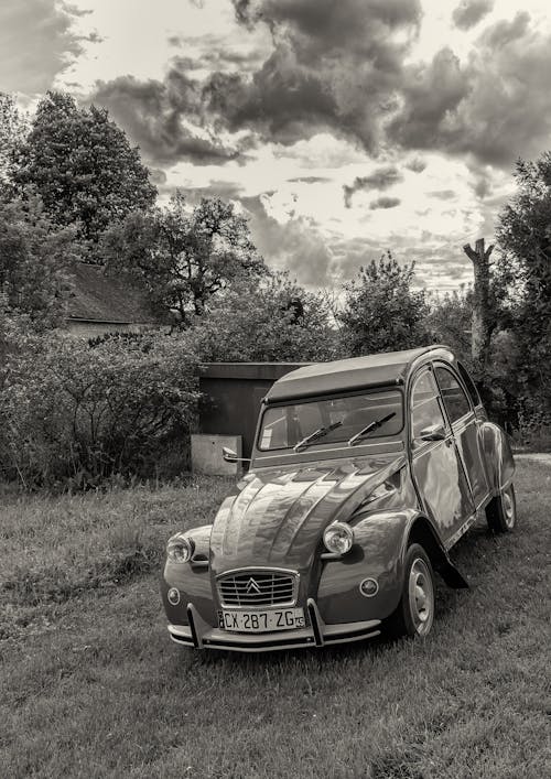 Black and White Photo of a Vintage Car on Lawn and Clouds in Sky