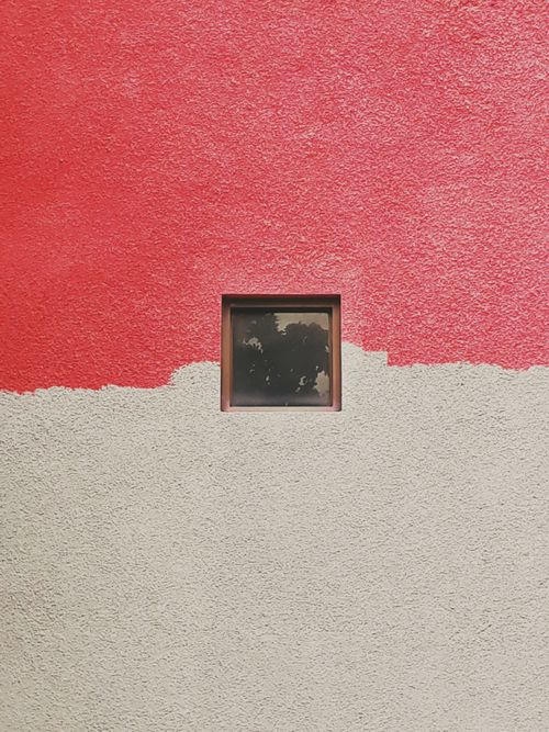 Free Minimalist photo of a red and white textured wall featuring a small square window. Stock Photo