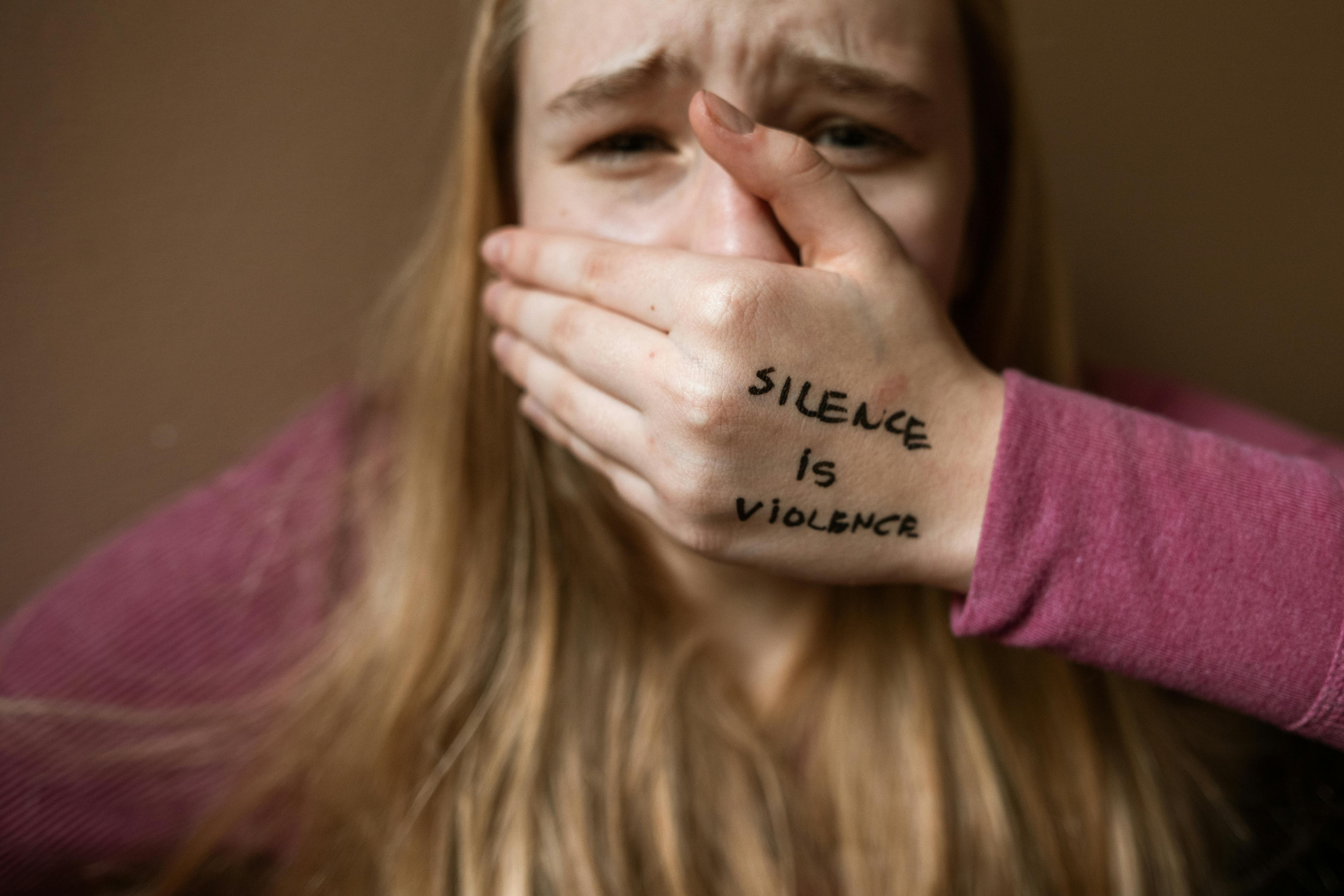 woman in purple shirt covering her face with her hand