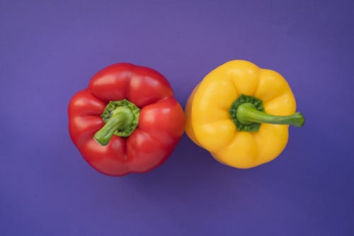 Free Red and Yellow Peppers on Purple Background Stock Photo