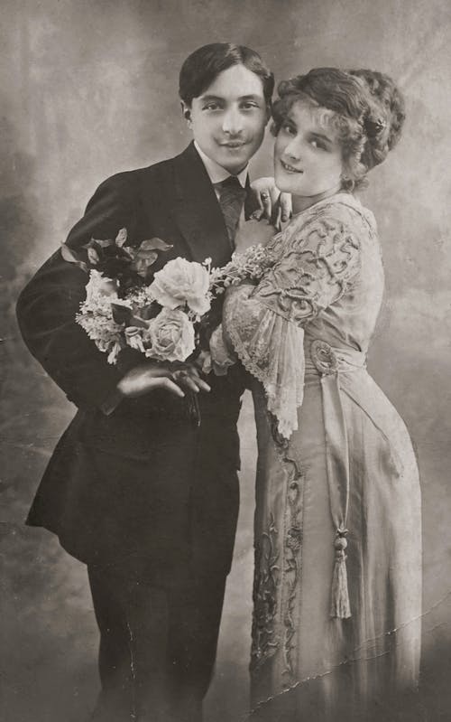 Man and Woman in Wedding Attire Holding Bouquet of Flowers
