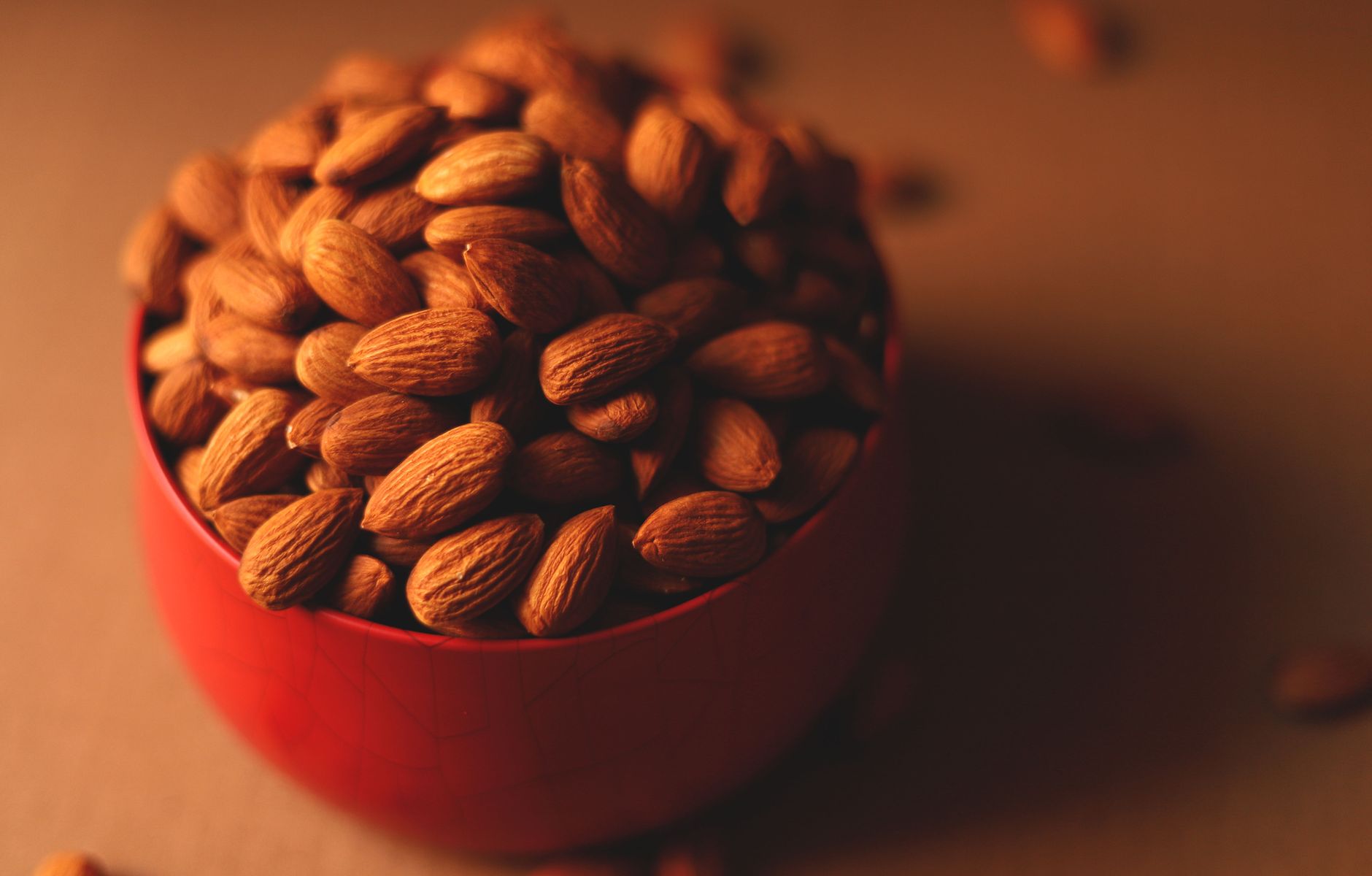A close-up of almonds in a red bowl, perfect for a healthy snack or nutritious eating.