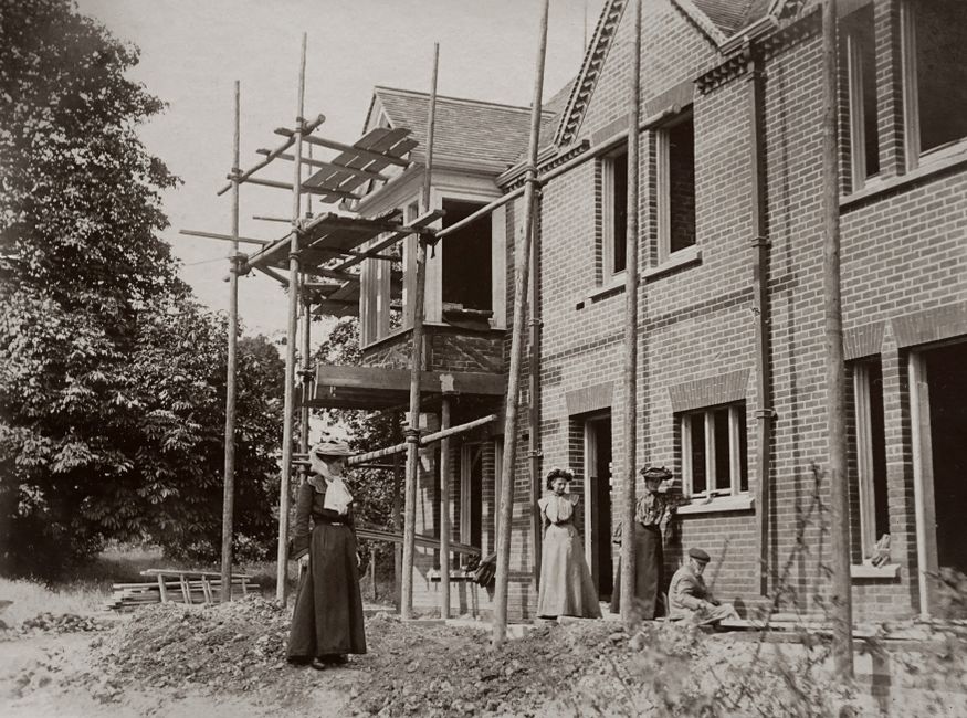 Vintage photo of an Edwardian house under construction with people observing.