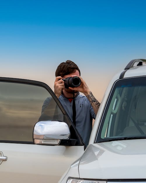 Anonymous man taking pictures of nature on photo camera at sunset