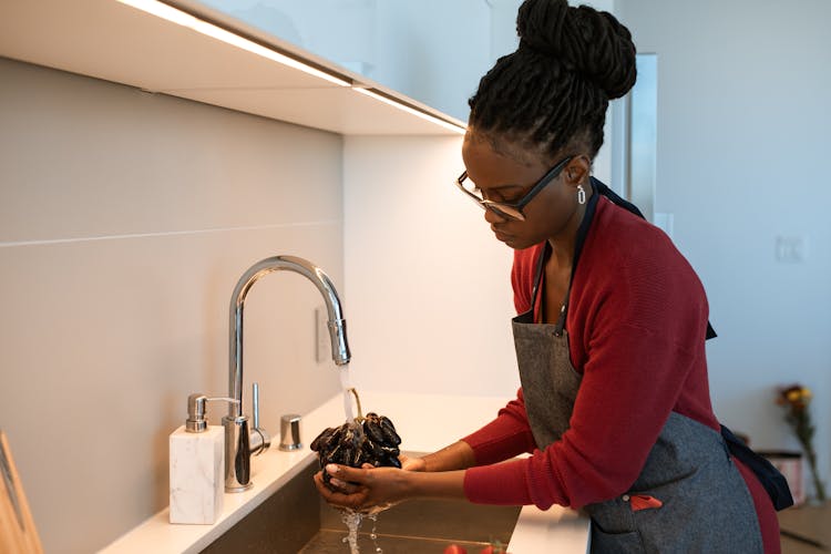 Woman Washing Grapes In Kitchen Sink