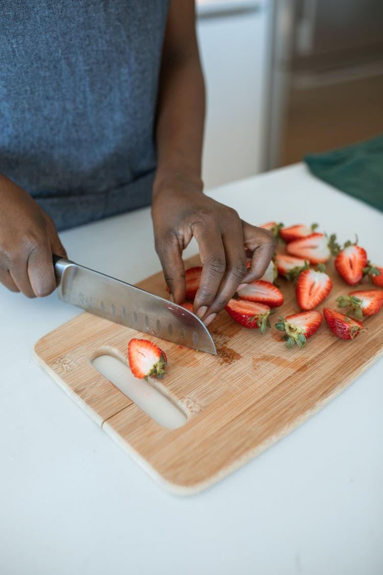 Person Slicing The Strawberries Into Half 