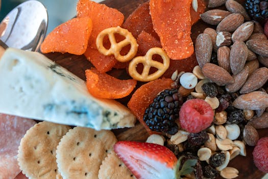 A close-up of a vibrant charcuterie board featuring cheese, nuts, fruits, and pretzels.