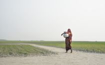 Woman Carrying a Earthen Jar in the Dirt Pathway