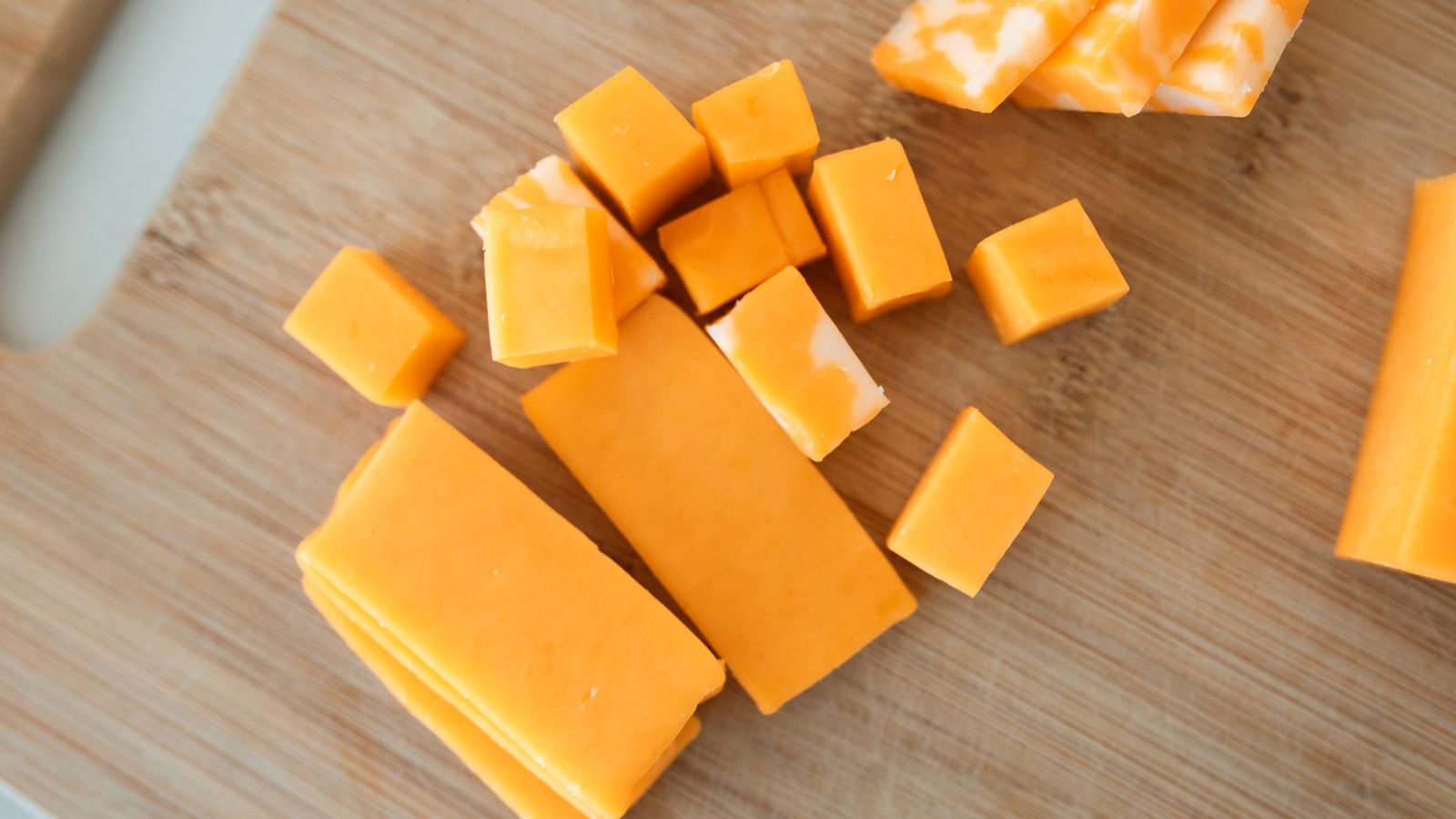 Cheddar cheese cubes and blocks on a wooden cutting board — photo by RDNE Stock project on Pexels Cheddar cheese cubes and blocks on a wooden cutting board