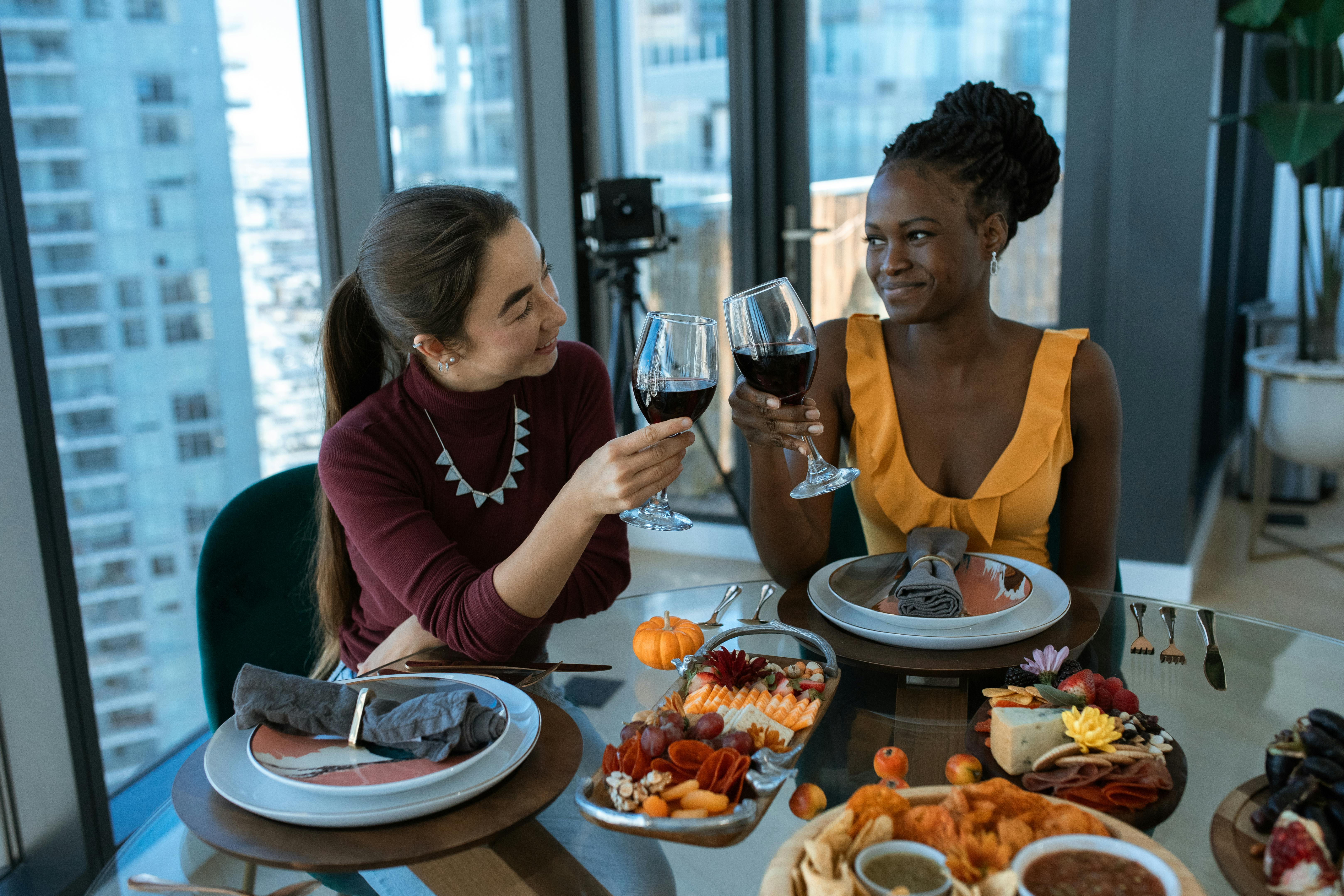 Free Two friends toast with wine over a beautifully arranged charcuterie and cheese platter. Stock Photo