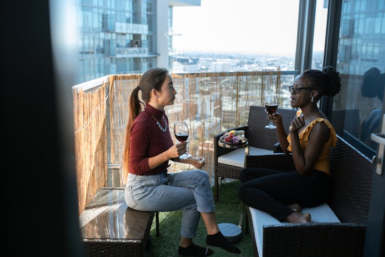 Two Women Drinking Wine In A Balcony