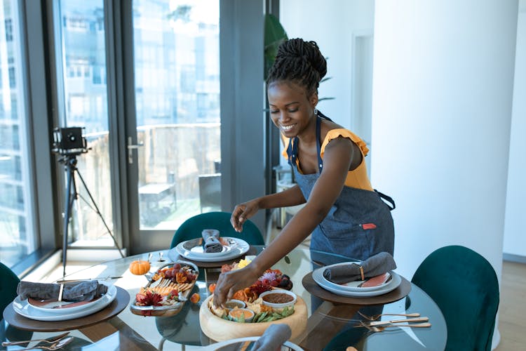 Smiling Woman Preparing Food On A Dining Table