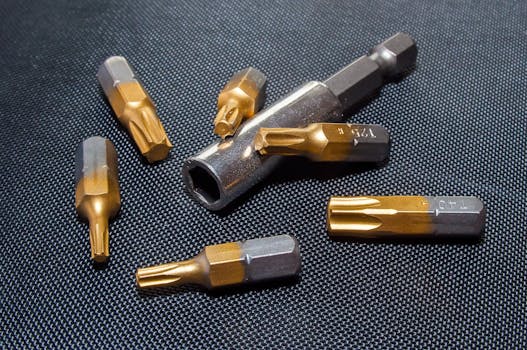A detailed close-up of metallic tool bits arranged on a dark textured surface.