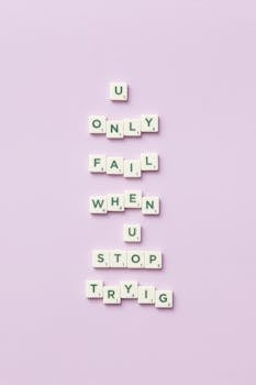 Inspirational Scrabble tile arrangement spelling 'U only fail when U stop trying' on lavender background.